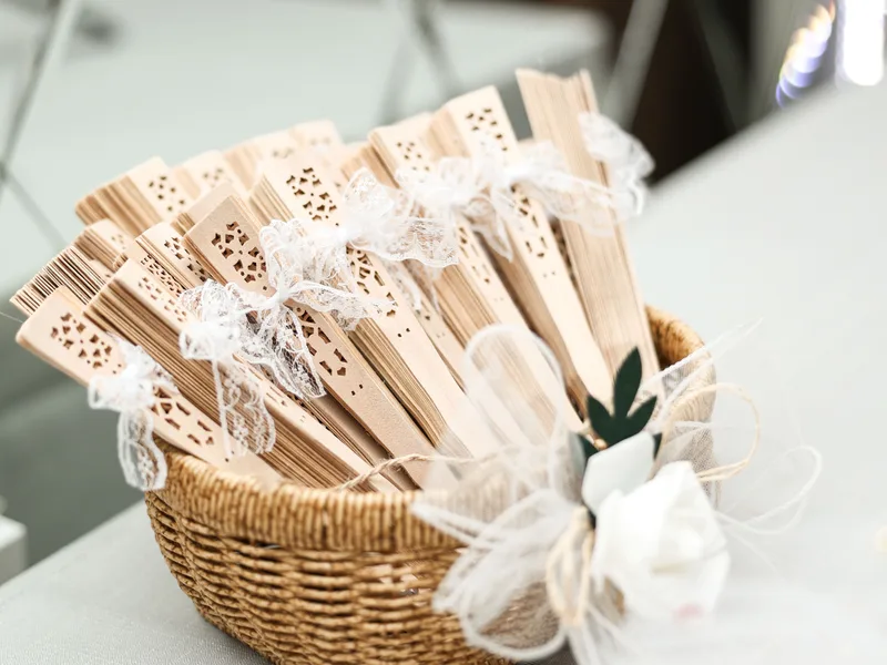 Éventails en bois avec dentelle pour mariage présentées dans un panier en osier